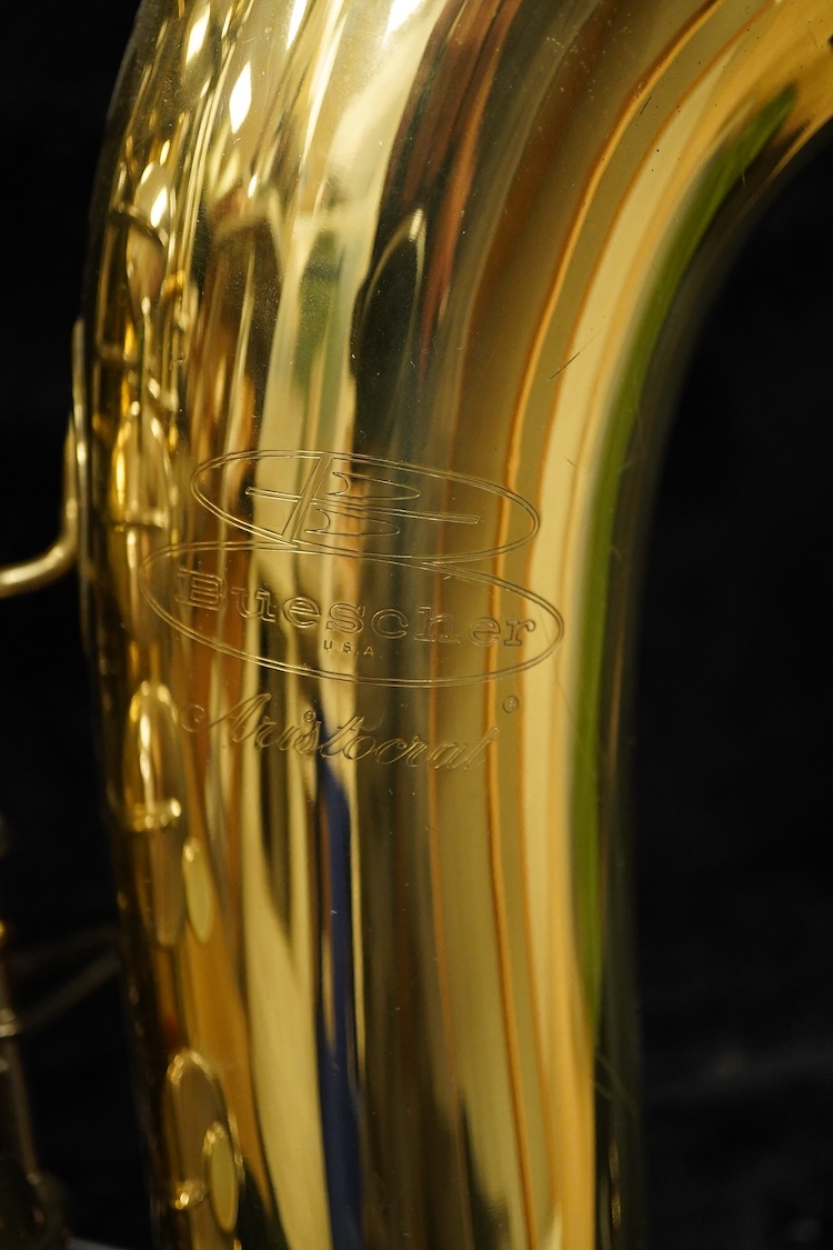 A cased Buescher Aristocrat tenor saxophone and stand